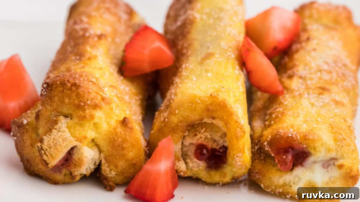15 Effortless Breakfasts for a Perfect Start 16 A close-up of golden brown air fryer French toast roll-ups, filled with sweet ingredients and served with fresh sliced strawberries on the side, highlighting a delicious and fun breakfast.