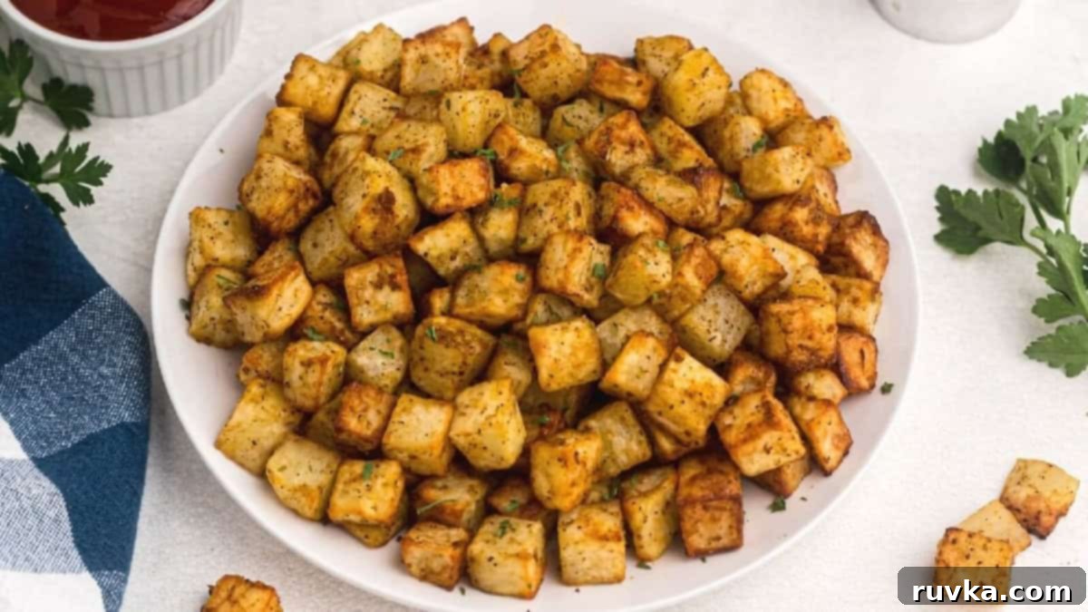 15 Effortless Breakfasts for a Perfect Start 3 Golden brown and crispy air fryer breakfast potatoes seasoned to perfection, served on a white plate, mimicking a restaurant-style side dish.