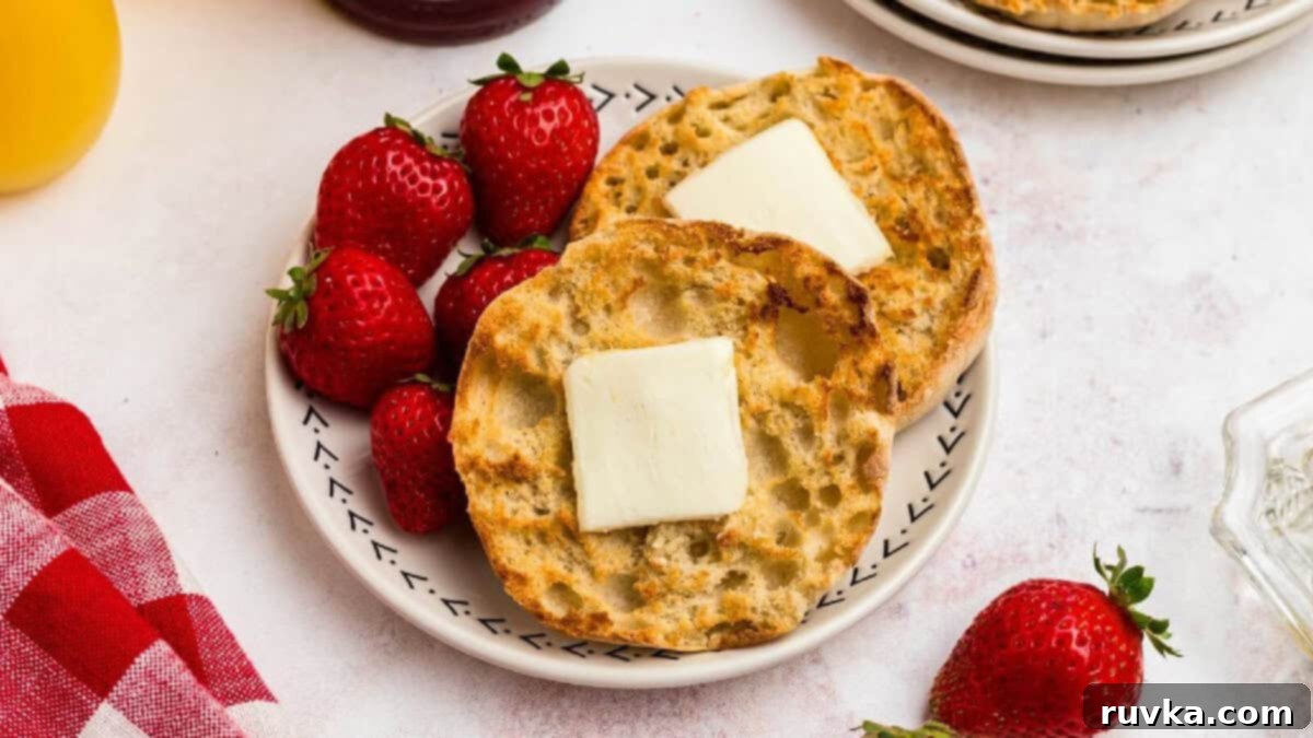 15 Effortless Breakfasts for a Perfect Start 9 Crispy air fryer English muffins, perfectly toasted and split, served on a plate with a melting pat of butter and fresh strawberries, highlighting a quick breakfast option.
