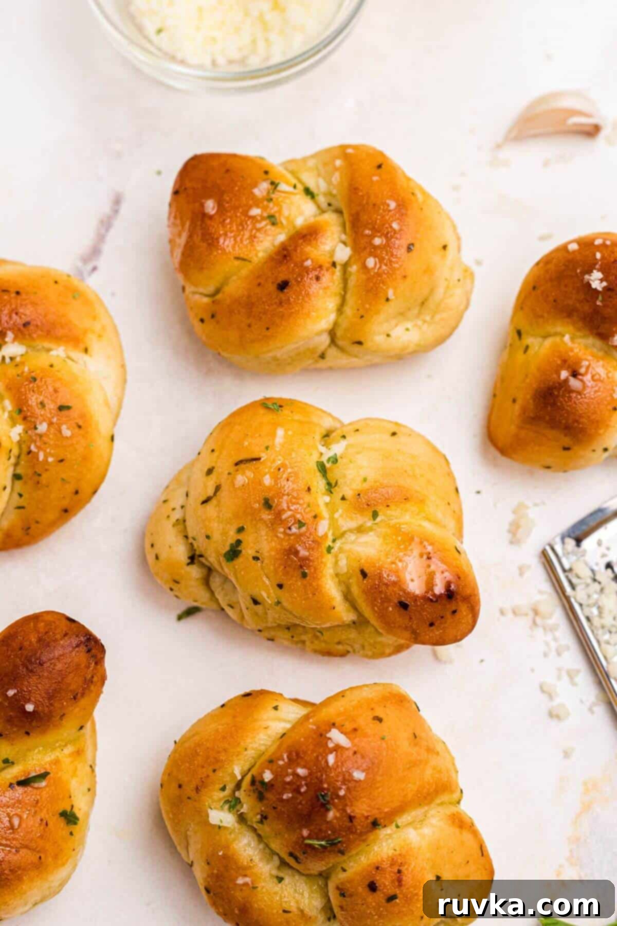 How to Air Fry Frozen Garlic Knots 2 Golden garlic knots brushed with olive oil and shredded cheese on a marble table.