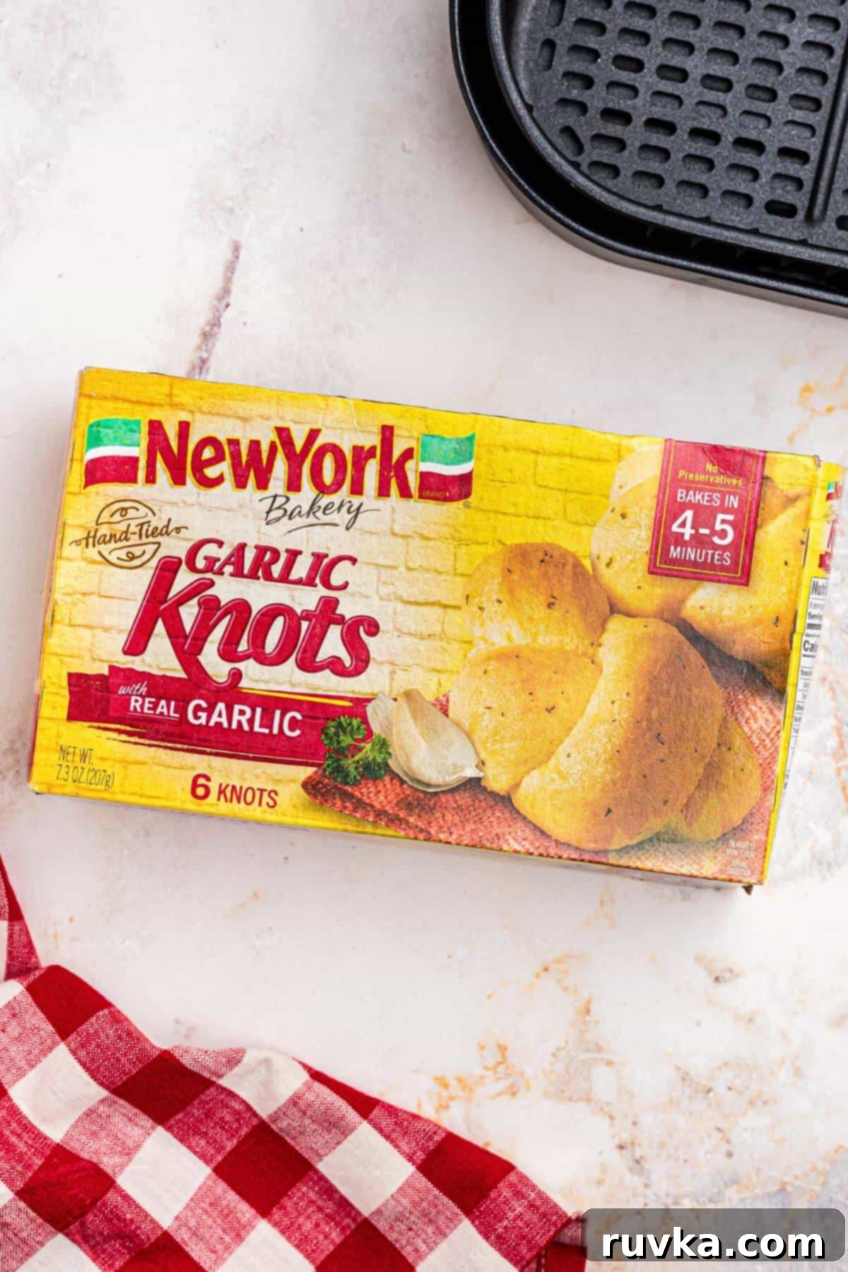 How to Air Fry Frozen Garlic Knots 3 One yellow box of New York Bakery brand garlic knots on a white marble table.