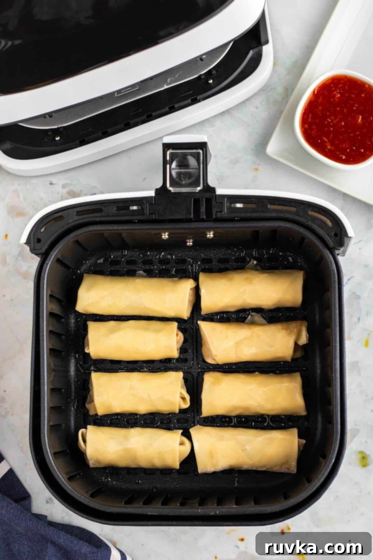 Crispy Air-Fried Egg Rolls 7 Uncooked rolled egg rolls in the air fryer basket.