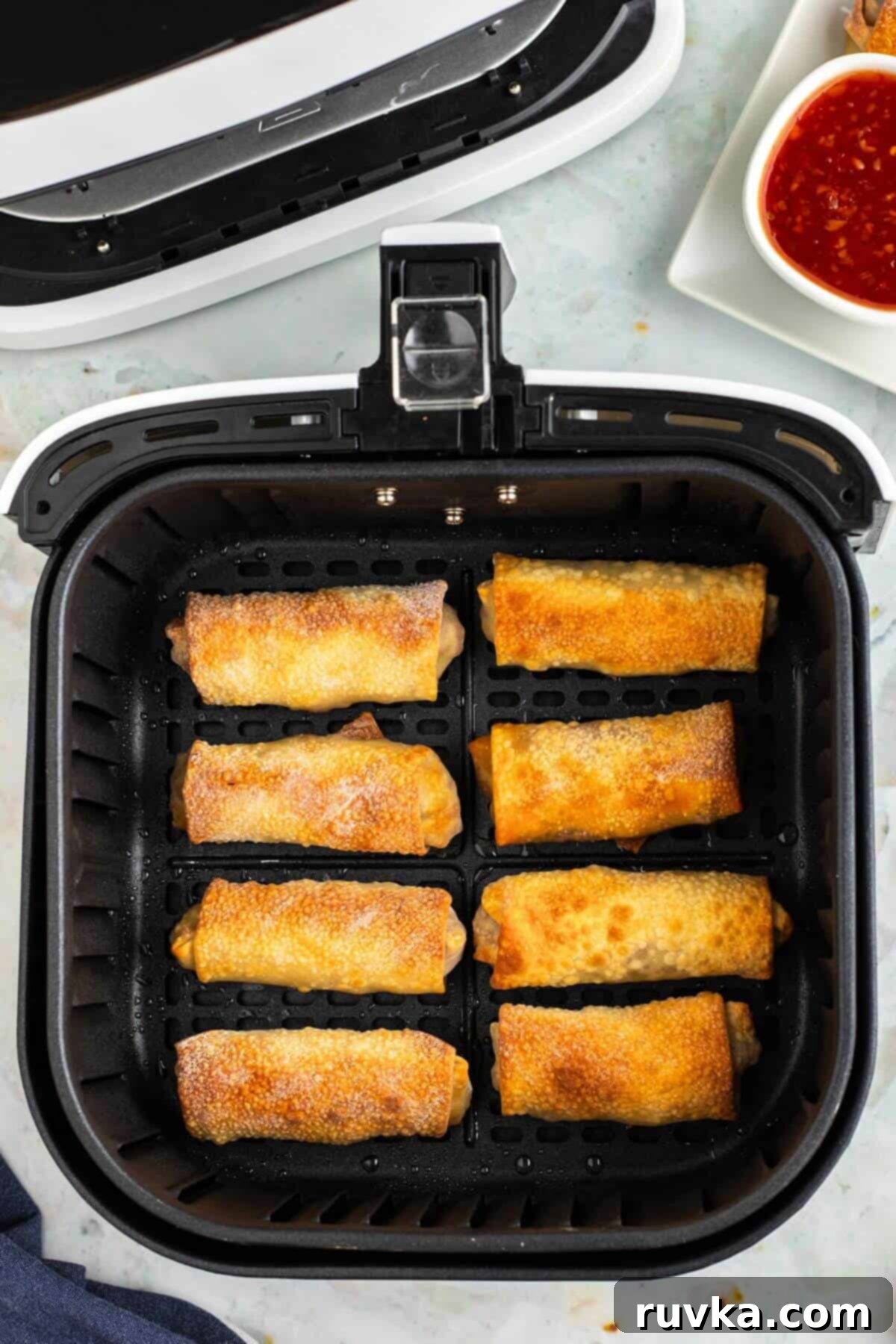 Crispy Air-Fried Egg Rolls 8 Golden egg rolls in the air fryer basket after being cooked.