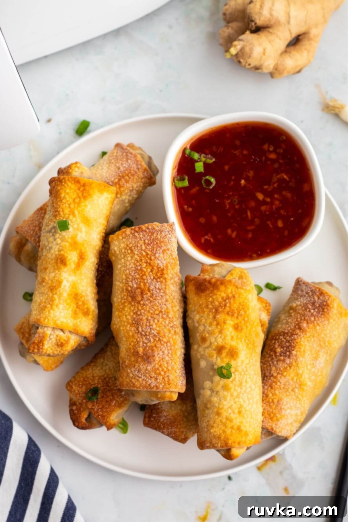 Crispy Air-Fried Egg Rolls 9 Golden crispy egg rolls on a white plate with cocktail sauce.