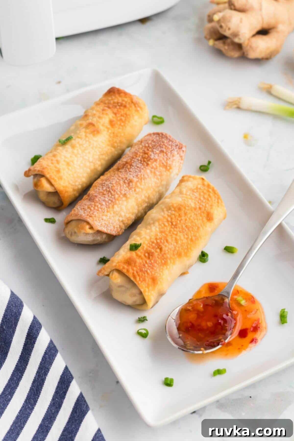 Crispy Air-Fried Egg Rolls 10 Golden crispy egg rolls on a white rectangle plate.