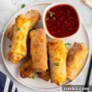 Crispy Air-Fried Egg Rolls 11 Golden crispy egg rolls on a white plate with cocktail sauce.