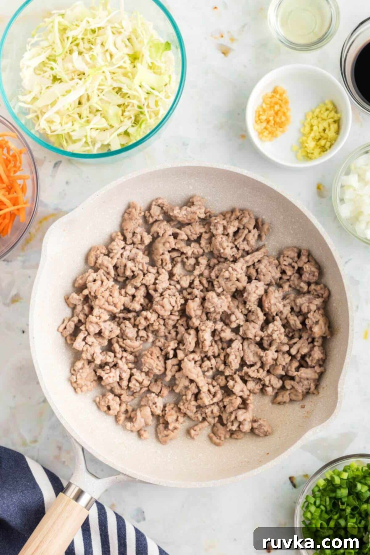 Crispy Air-Fried Egg Rolls 4 ground pork cooked in a frying pan with other ingredients measured around the table.