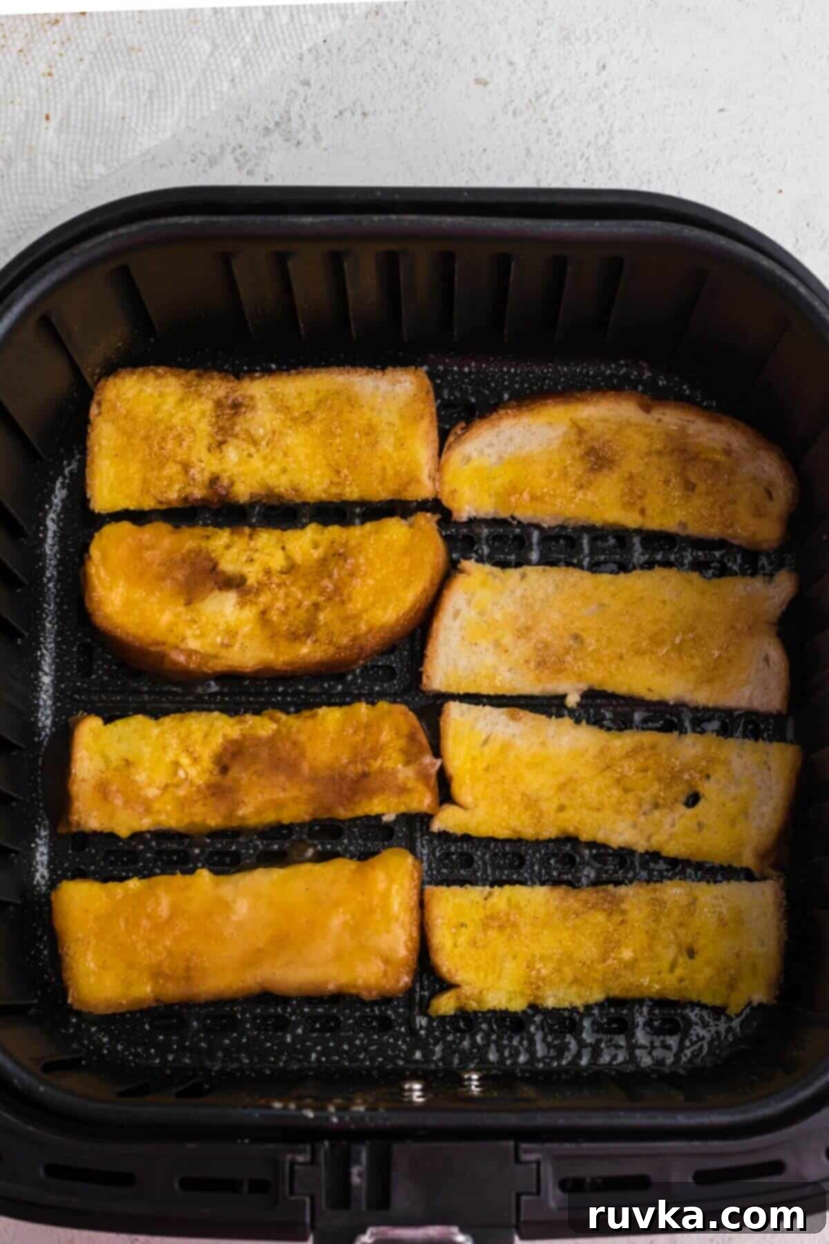 Golden Air Fryer French Toast Sticks 6 Dipped bread sliced placed in a single layer in the air fryer basket.