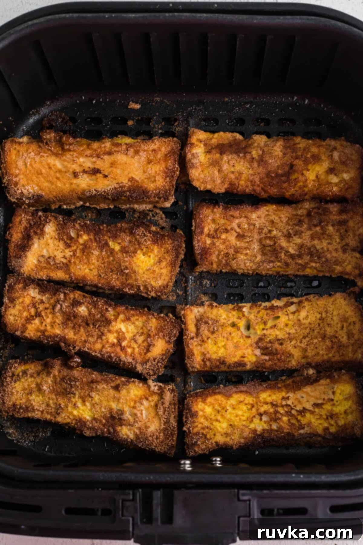 Golden Air Fryer French Toast Sticks 7 French toast sticks in air fryer basket ready to serve.