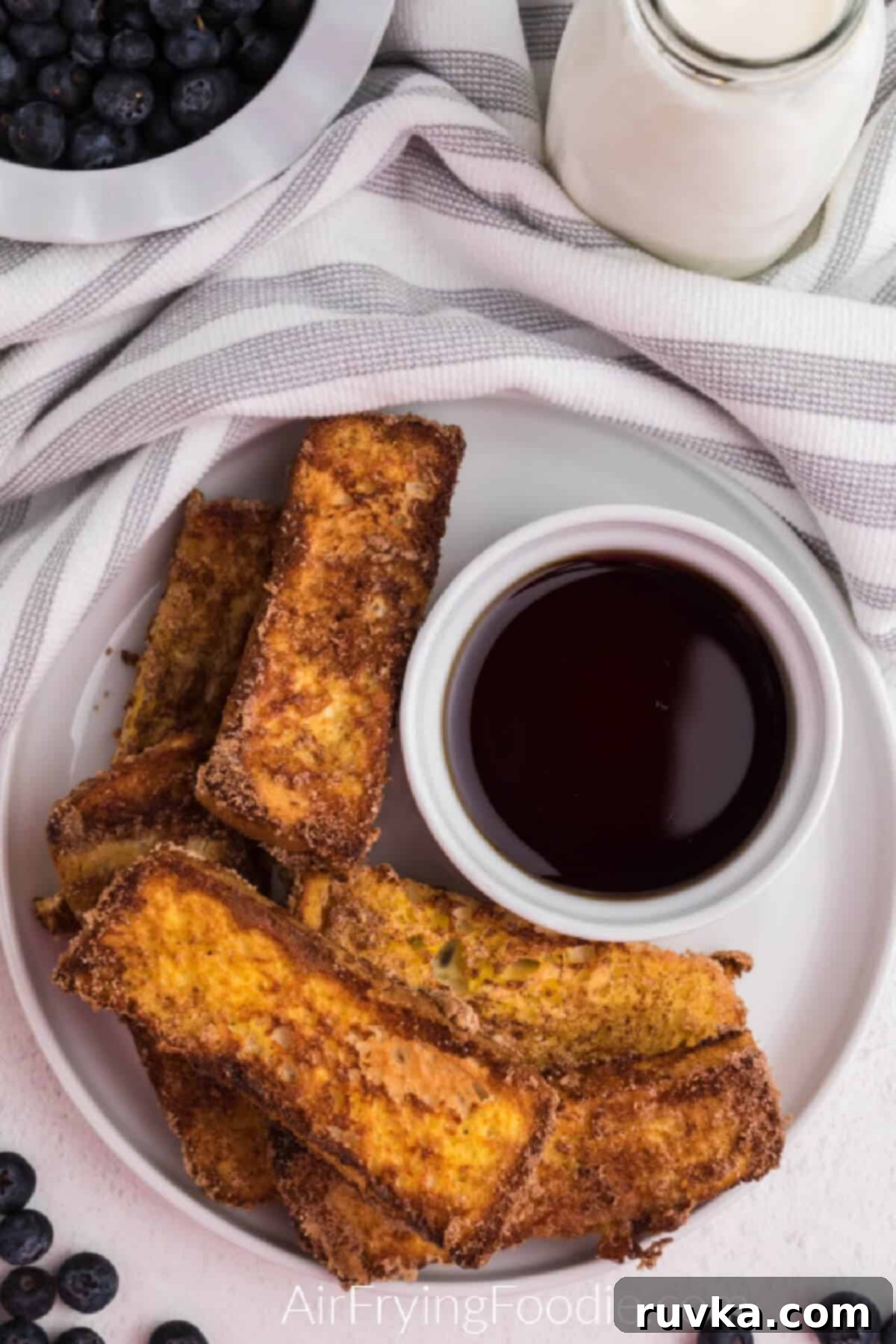Golden Air Fryer French Toast Sticks 9 Overhead shot of french toast sticks made in the air fryer with a side of syrup for dipping.