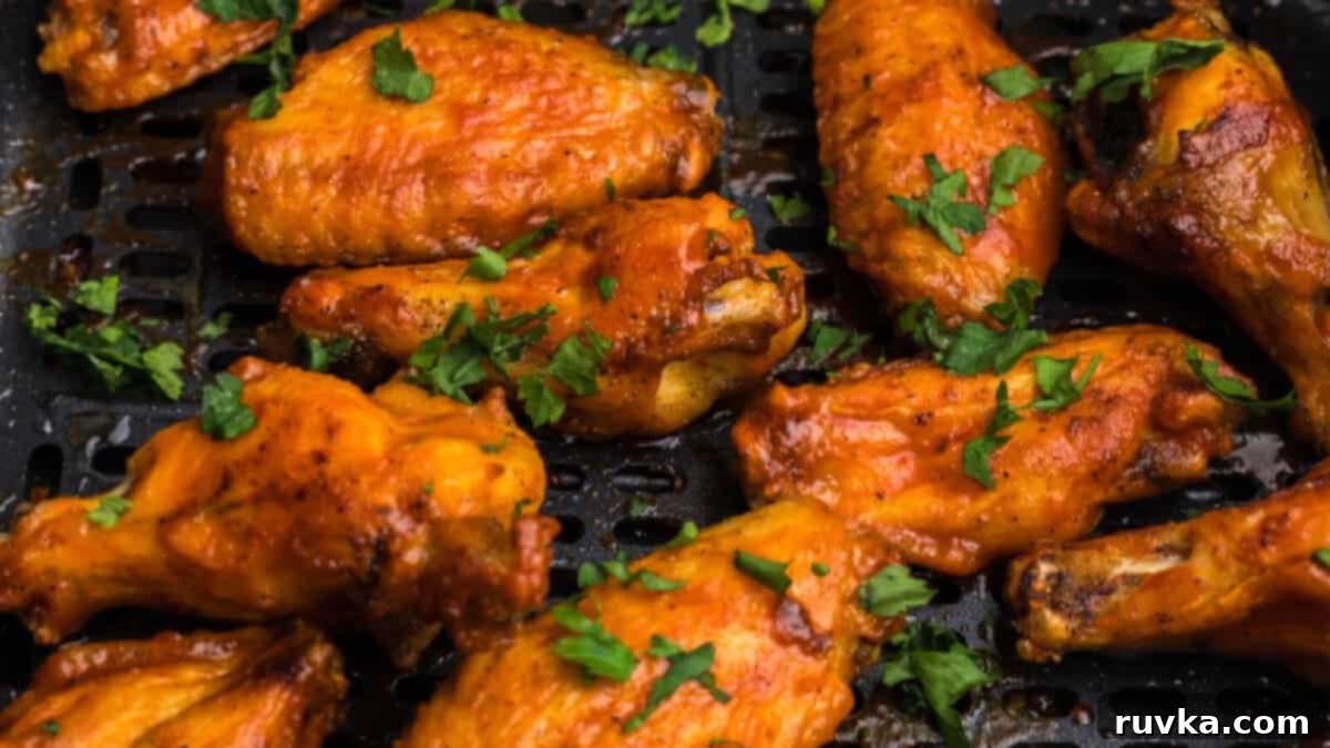 Epic Tailgate Bites Your Friends Will Love 2 crispy chicken wings in the air fryer basket topped with fresh parsley.
