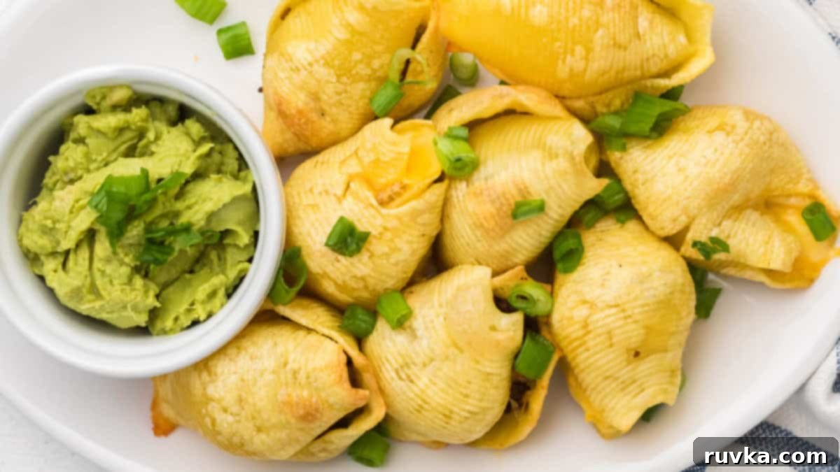 Epic Tailgate Bites Your Friends Will Love 11 Taco stuffed shells on a serving tray with a side of guacamole in a small bowl.