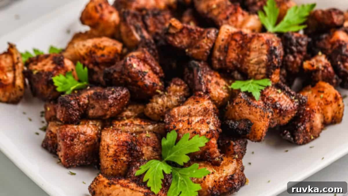 Epic Tailgate Bites Your Friends Will Love 13 pork belly garnished with parsley sprigs and served on a white tray.