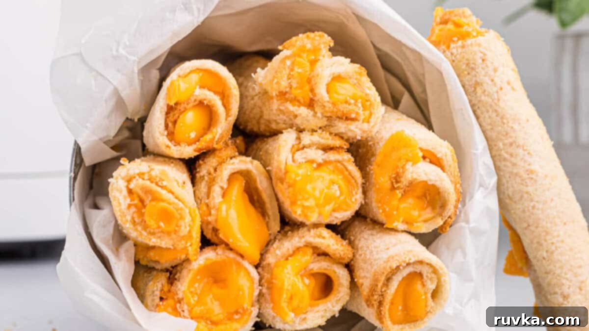 Epic Tailgate Bites Your Friends Will Love 6 grilled cheese roll ups in paper, with one propped up on the side. Ready to eat.