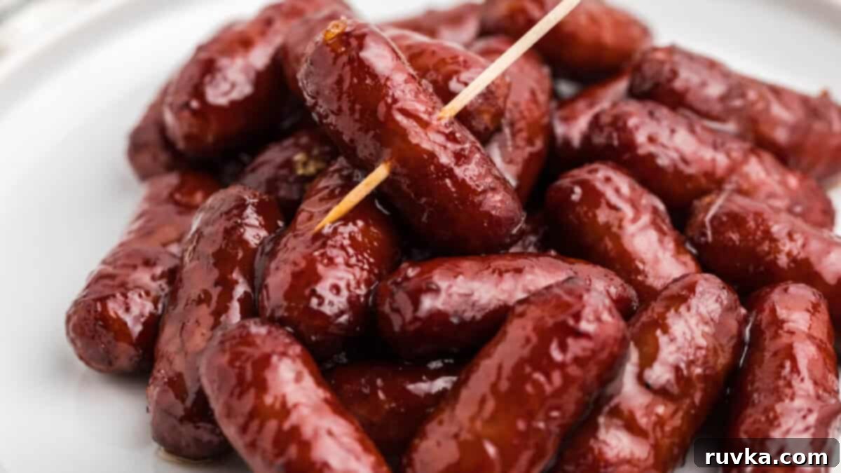 Epic Tailgate Bites Your Friends Will Love 7 BBQ lil smokies on a white plate, a toothpick inserted through the top of one.