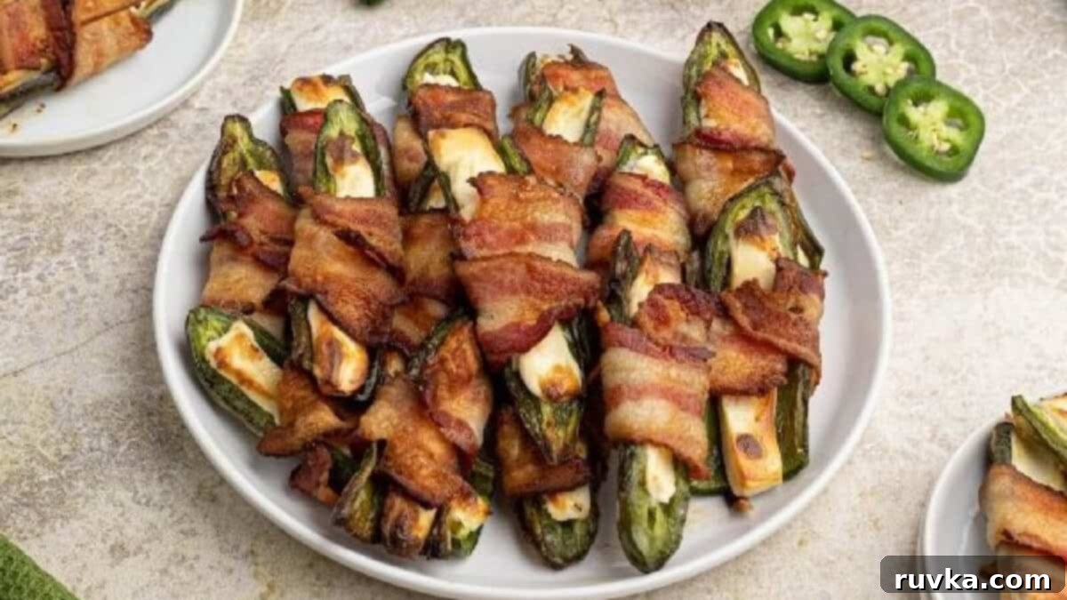 Epic Tailgate Bites Your Friends Will Love 10 Jalapeno poppers on a white plate with sliced jalapenos on the side.