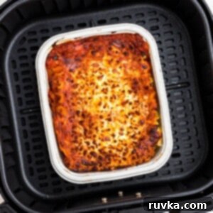 Perfect Air Fryer Frozen Lasagna 8 Juicy lasagna in a small tray in the air fryer basket.