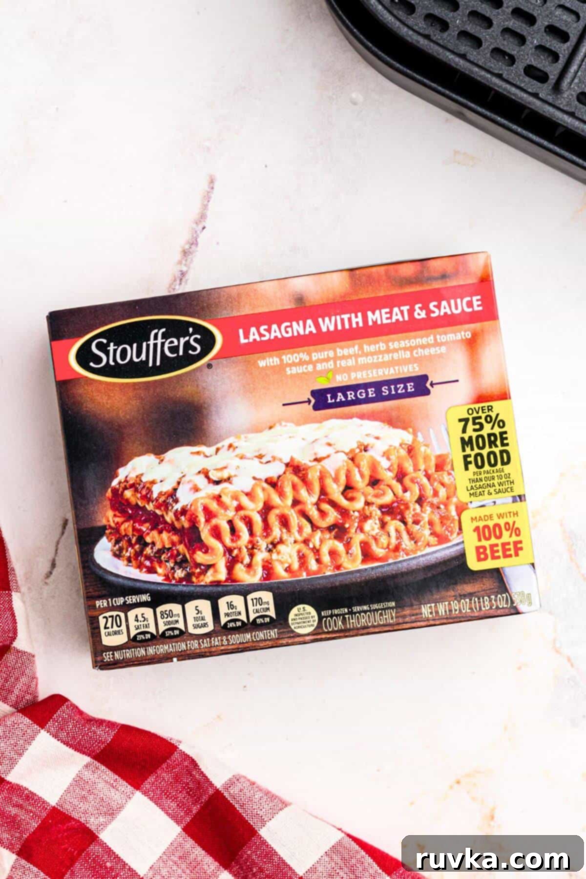 Perfect Air Fryer Frozen Lasagna 3 Box of frozen lasagna on a white marble table in front of the air fryer basket.