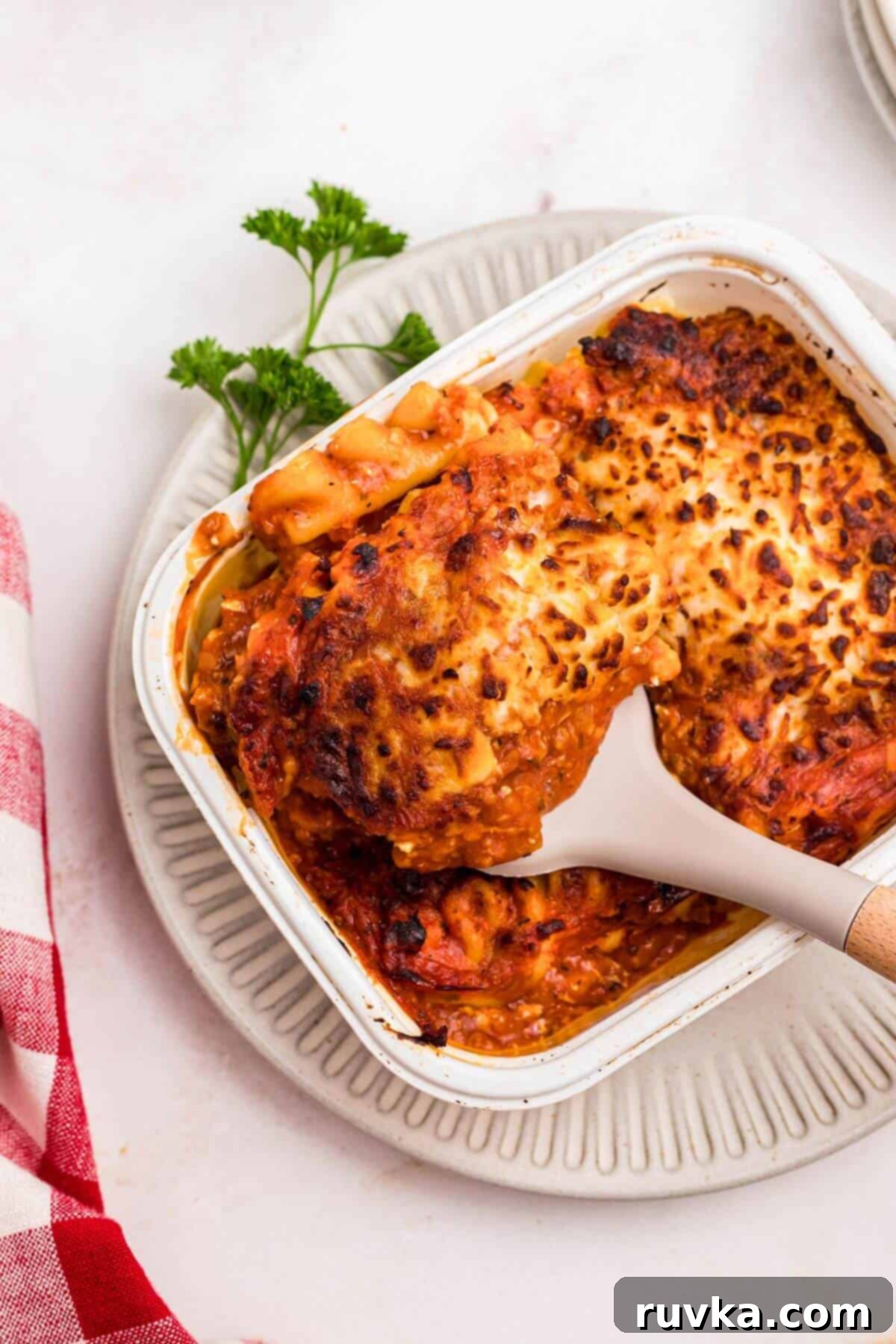 Perfect Air Fryer Frozen Lasagna 6 Juicy lasagna in a small tray being lifted out of the container with a spatula.