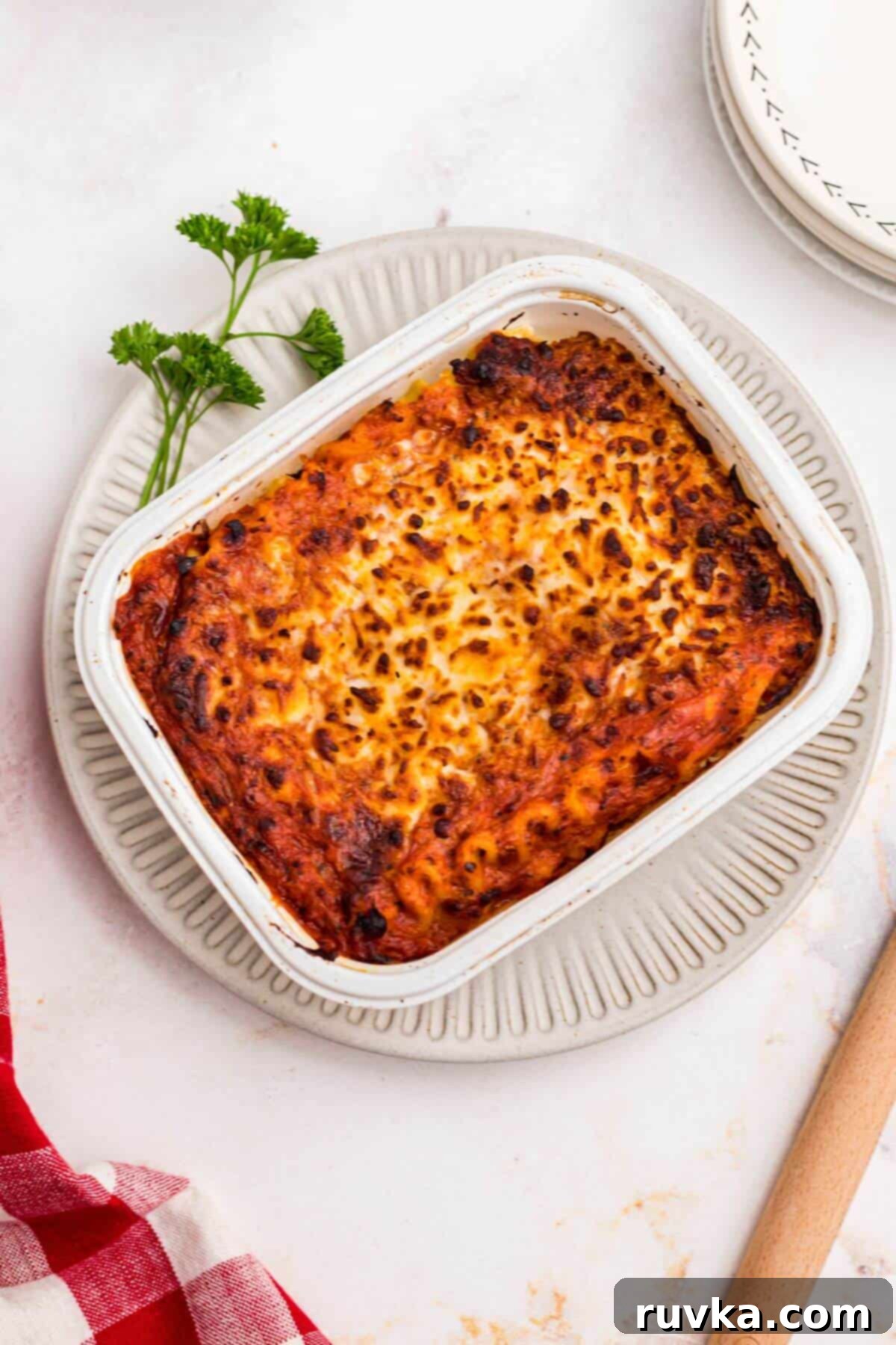 Perfect Air Fryer Frozen Lasagna 7 Juicy lasagna in a small tray on a white plate garnished with parsley.