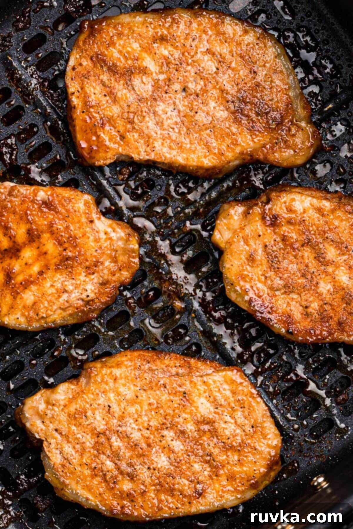No-Thaw Air Fryer Pork Chops 8 Golden juicy seasoned pork chops in the air fryer after being cooked.
