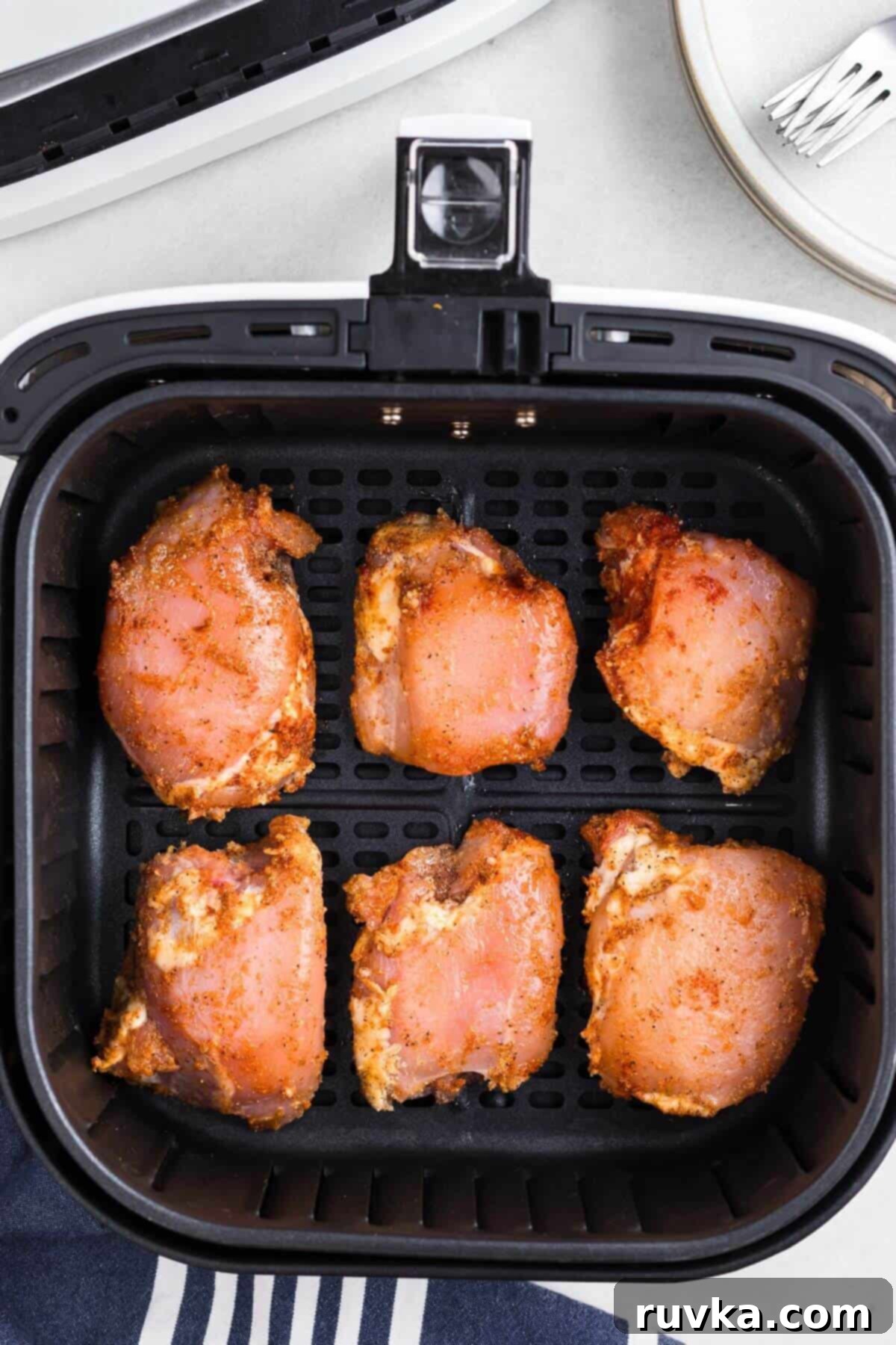 Freezer to Fabulous Air Fryer Chicken Thighs 5 Seasoned uncooked chicken thighs in an air fryer basket