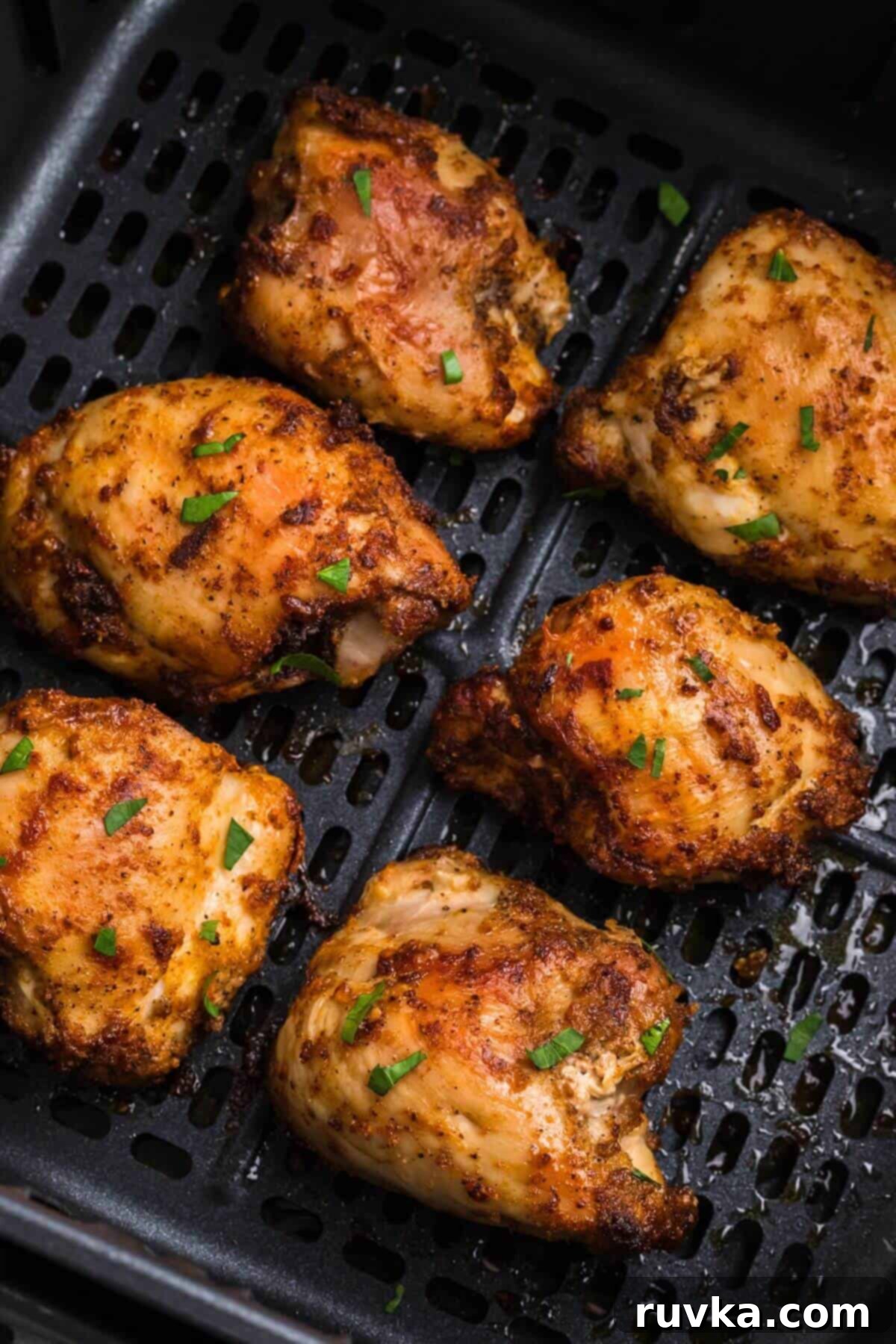 Freezer to Fabulous Air Fryer Chicken Thighs 6 Golden brown crispy chicken thighs in the air fryer basket after being cooked.