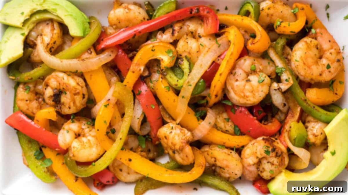 15 Foolproof Air Fryer Recipes 2 shrimp fajitas mixture with bell peppers, onion, and shrimp, with sliced avocados on a white serving plate.