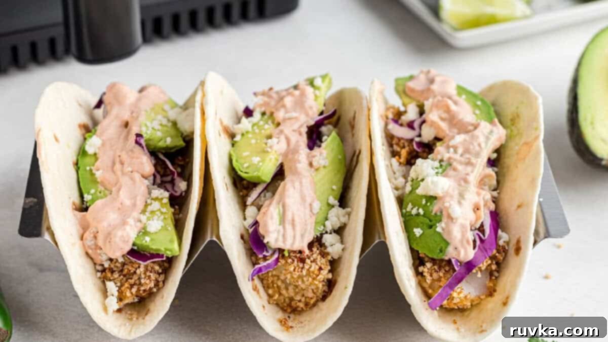 15 Foolproof Air Fryer Recipes 14 fish tacos made in the air fryer and served on a taco tray with sliced avocado and sauce on a flour tortilla.