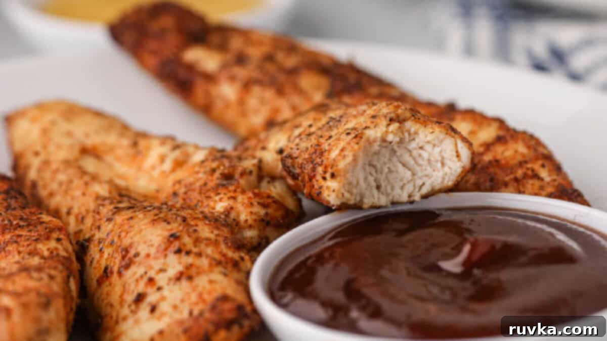 15 Foolproof Air Fryer Recipes 4 air fryer naked chicken tenders on a white plate with a side of dipping sauce.