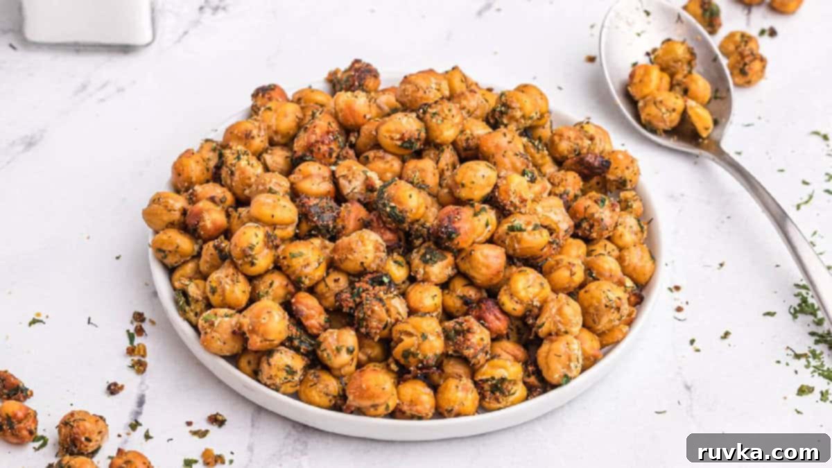 15 Foolproof Air Fryer Recipes 10 crispy chickpeas on a white plate with some on a spoon in the background.