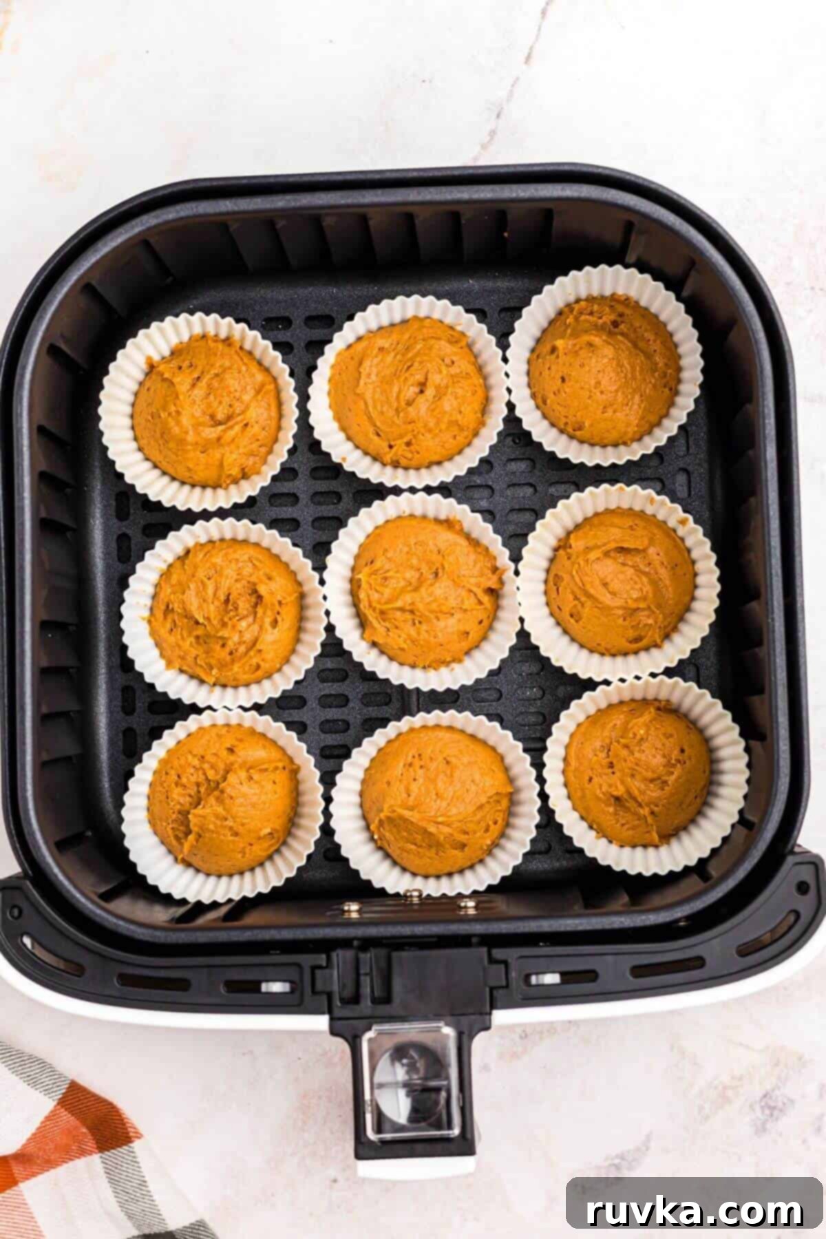Easy Air Fryer 2 Ingredient Pumpkin Muffins 7 Uncooked muffin batter in silicone liners, in the air fryer basket.
