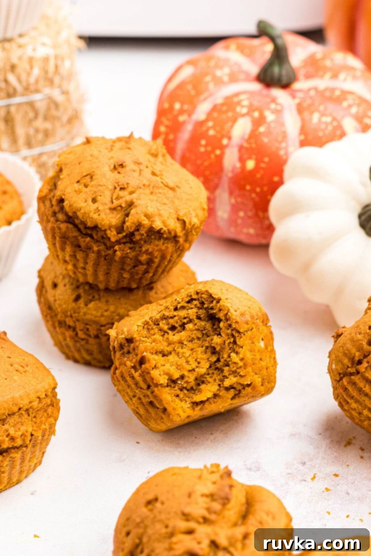 Easy Air Fryer 2 Ingredient Pumpkin Muffins 9 Moist pumpkin muffins stacked on top of each other with one muffin in front with a bite missing.