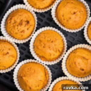 Easy Air Fryer 2 Ingredient Pumpkin Muffins 11 Moist orange pumpkin muffins in silicone liners in the air fryer basket.