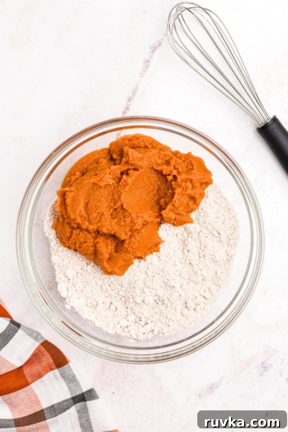Easy Air Fryer 2 Ingredient Pumpkin Muffins 4 Pumpkin puree and spice cake mix in a clear glass mixing bowl, before being combined.