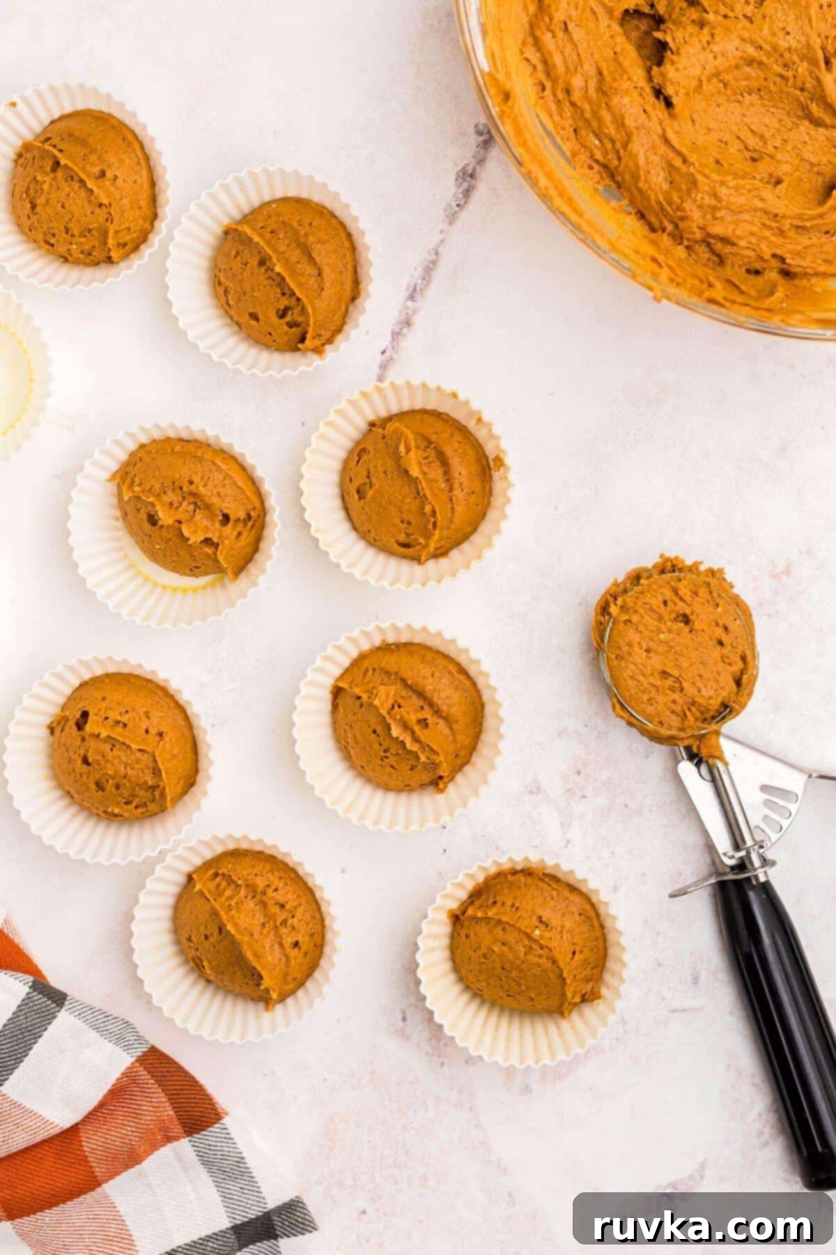 Easy Air Fryer 2 Ingredient Pumpkin Muffins 6 Pumpkin muffin batter scooped out and place into silicone muffin liners, on a white marble table
