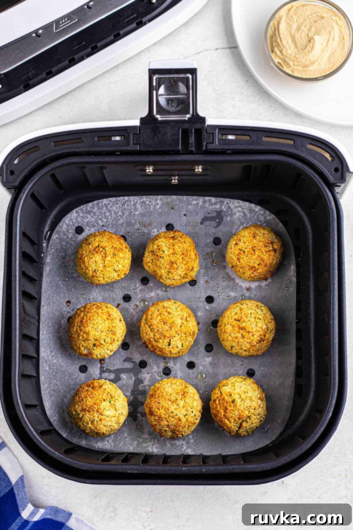 Air Fryer Parchment Hacks for Effortless Cooking 6 Golden brown cooked falafels, perfectly crispy, arranged in an air fryer basket on a sheet of parchment paper.