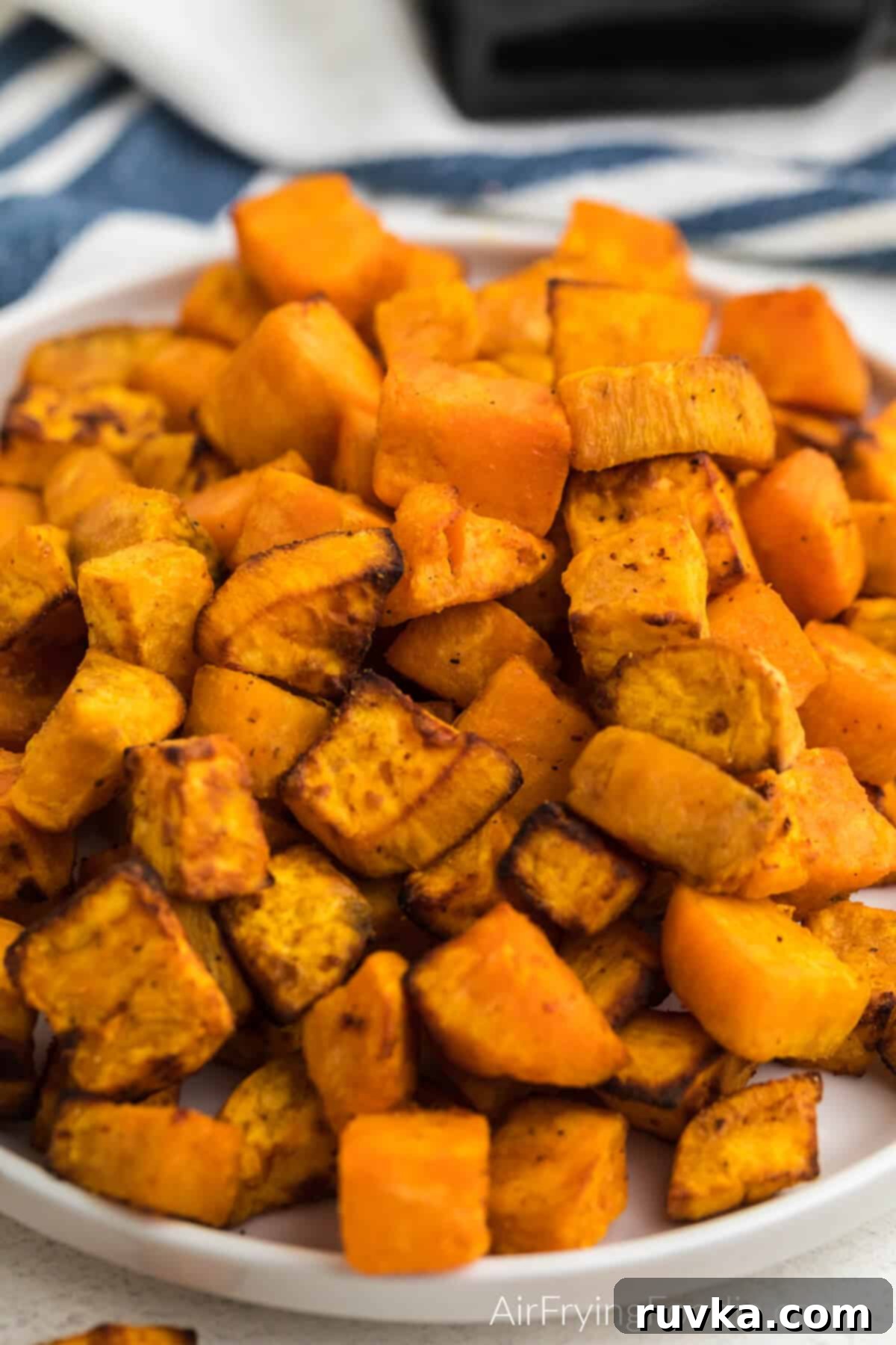 Crispy Air-Fried Sweet Potato Cubes 2 Close up photo of air fryer sweet potato cubes on a white plate, ready to eat.