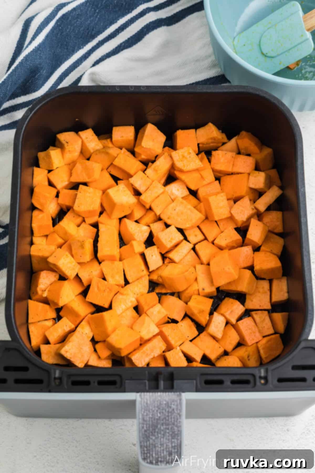 Crispy Air-Fried Sweet Potato Cubes 7 Oiled and seasoned sweet potato cubes in air fryer basket, ready to be cooked.
