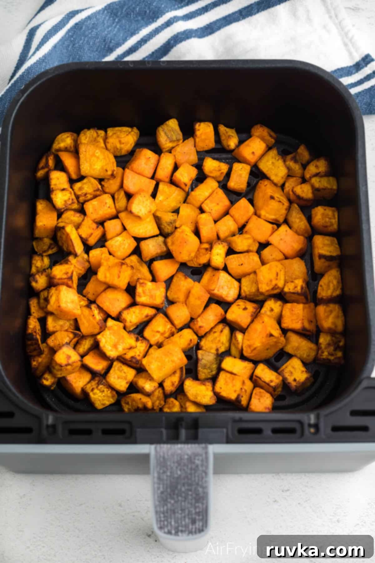 Crispy Air-Fried Sweet Potato Cubes 8 Air fried sweet potato cubes in the basket of the air fryer.
