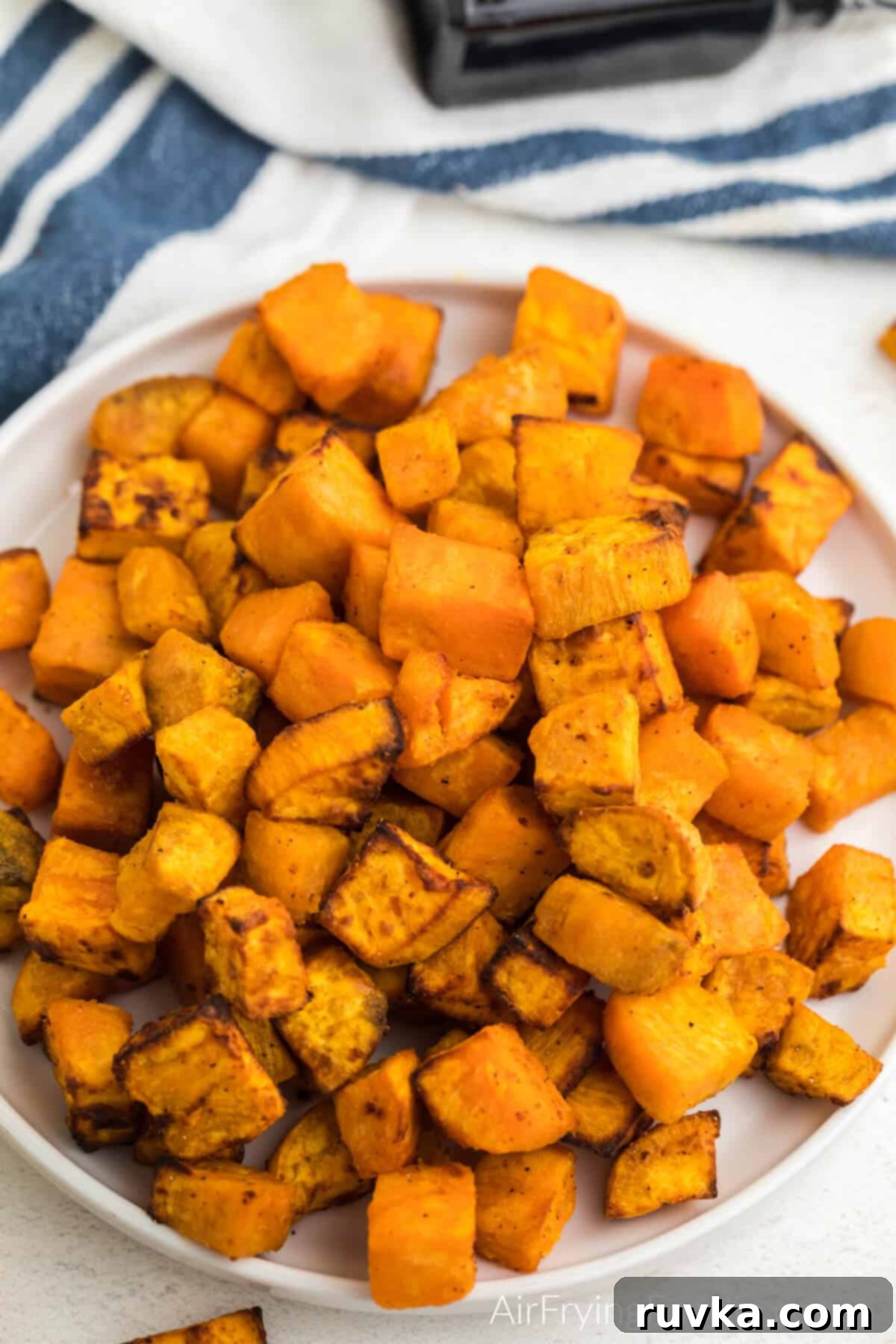 Crispy Air-Fried Sweet Potato Cubes 10 Close up overhead angle photo of air fryer sweet potato cubes served on a white plate.