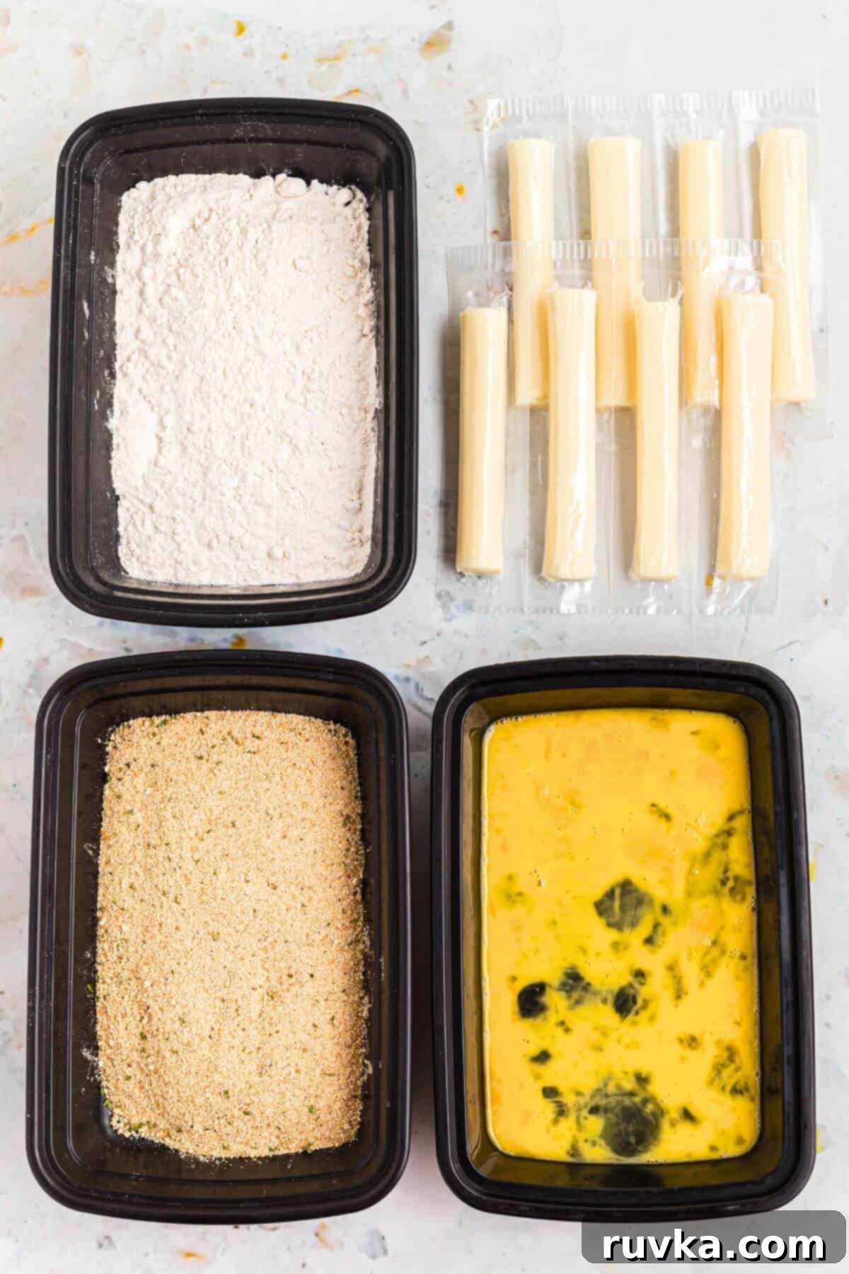 Crispy Air Fryer Mozzarella Sticks 3 Flour, breadcrumbs, eggs, and cheese sticks on a marble table.