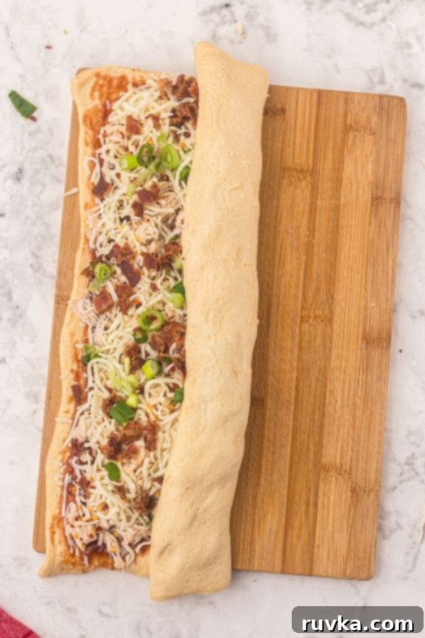 Crispy Air Fryer BBQ Chicken Pizza Rolls 4 Rolled dough shaped into rectangle, then topped with sauce and cheese, shredded chicken, halfway rolled up.