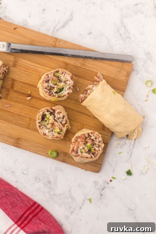 Crispy Air Fryer BBQ Chicken Pizza Rolls 5 Air Fryer BBQ Chicken Pizza Rolled dough filled and then cut into circles on a cutting boards.