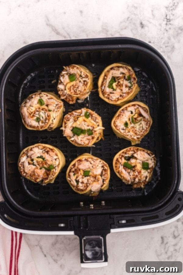 Crispy Air Fryer BBQ Chicken Pizza Rolls 6 Uncooked rolled air fryer BBQ chicken pizza roles in the air fryer basket.
