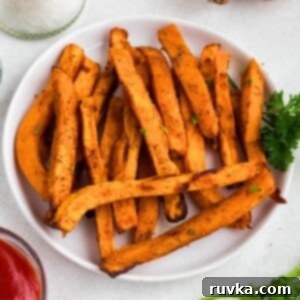 Crispy Air Fryer Sweet Potato Fries 9 Sweet potato fries on a white round plate with small dish of ketchup.