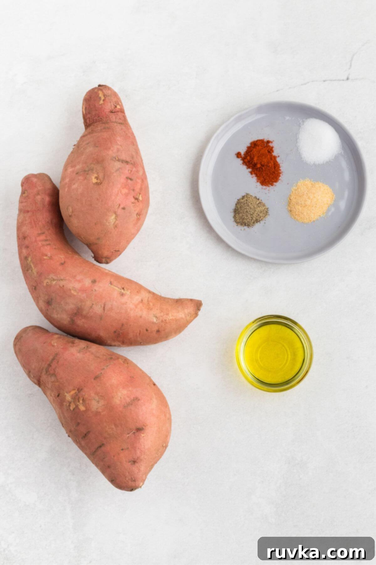 Crispy Air Fryer Sweet Potato Fries 3 Sweet potatoes, olive oil, and seasonings on a white marble table.