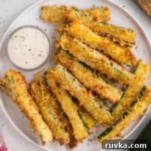 Guilt-Free Air Fryer Zucchini Fries 9 Golden crispy zucchini fries stacked on a white plate.