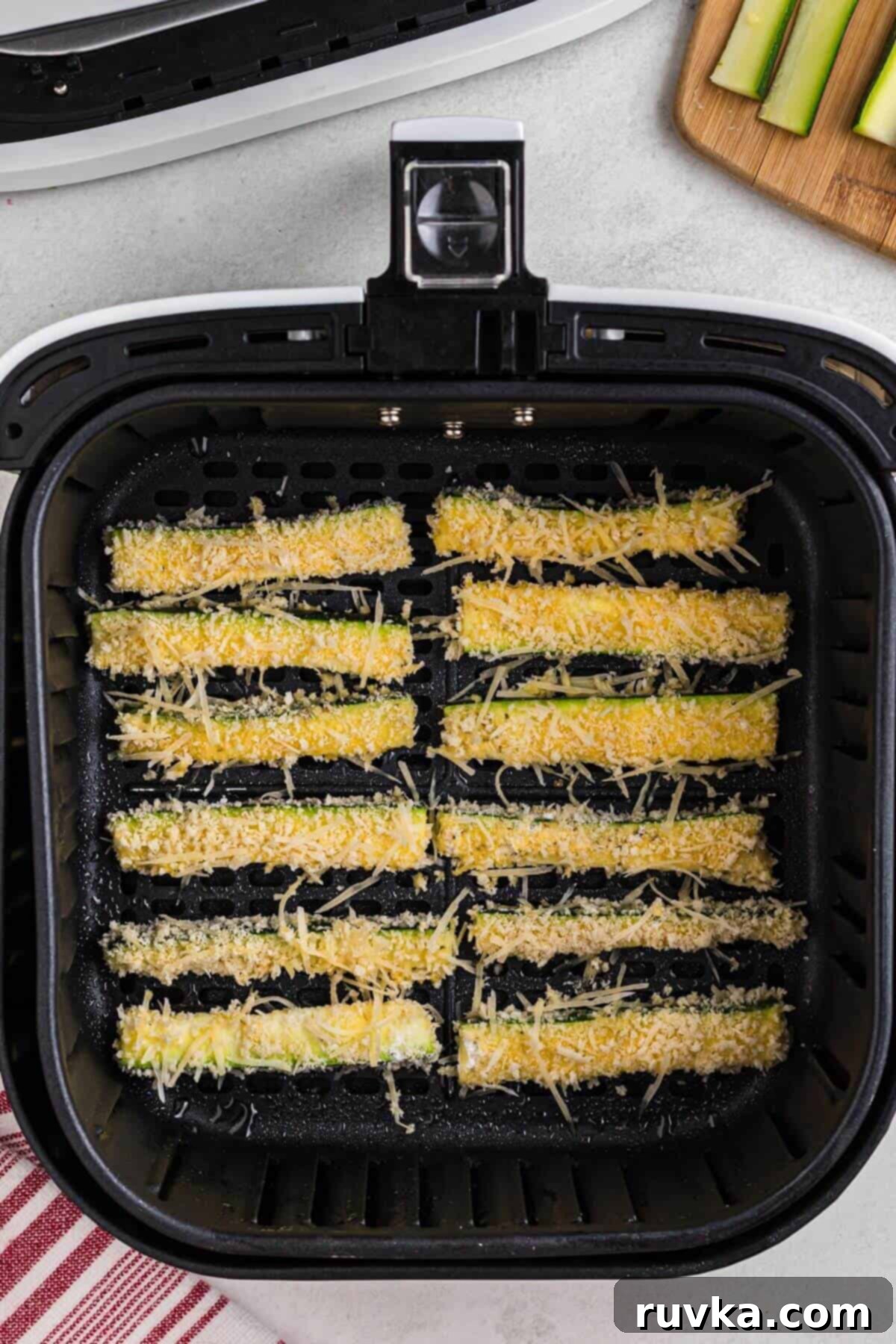 Guilt-Free Air Fryer Zucchini Fries 6 Zucchini sticks breaded and placed in the air fryer basket before being cooked.