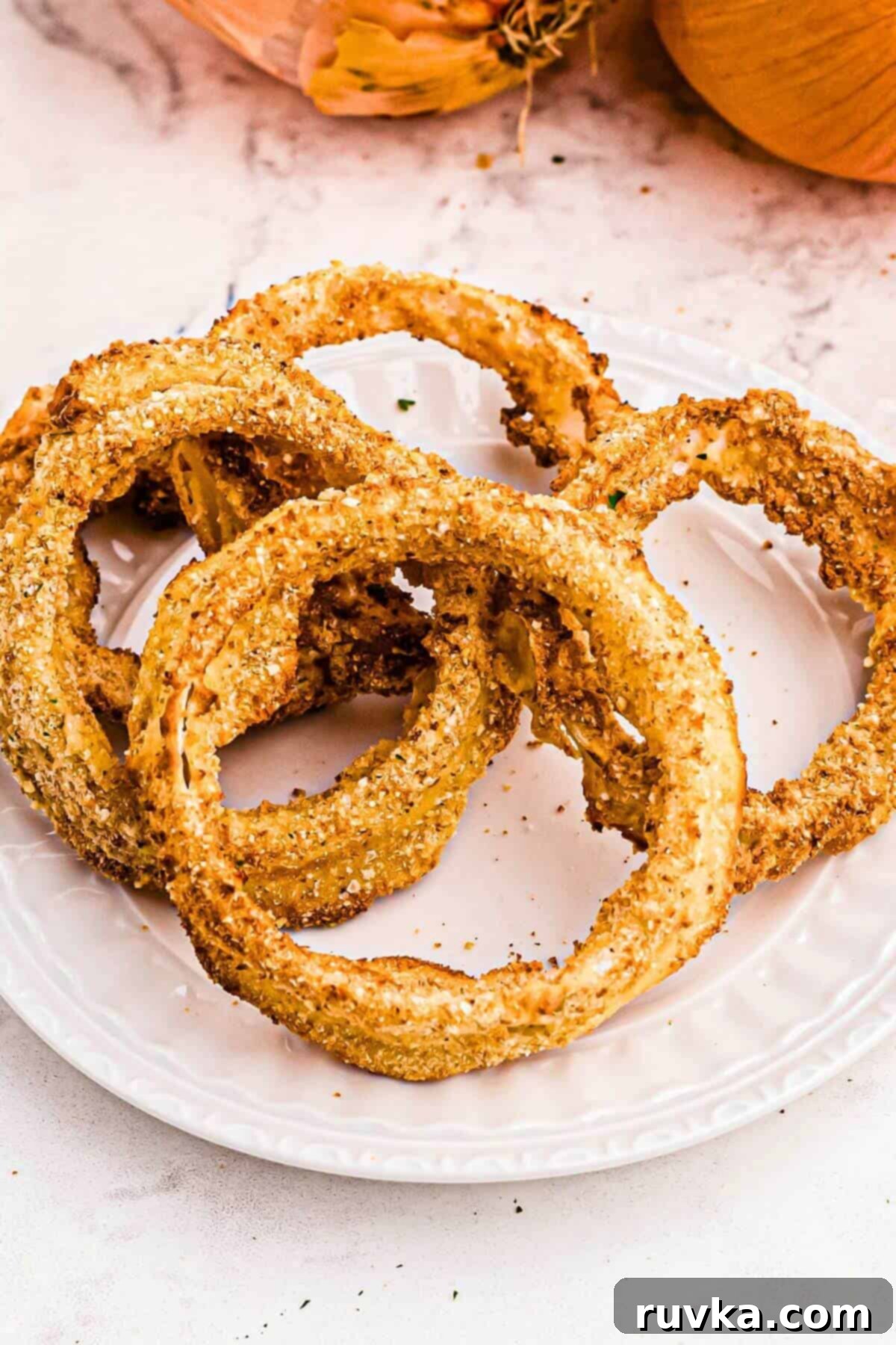 Bring Back the Crunch Air Frying Onion Rings 4 air fryer onion rings stacked on a white plate, ready to eat.